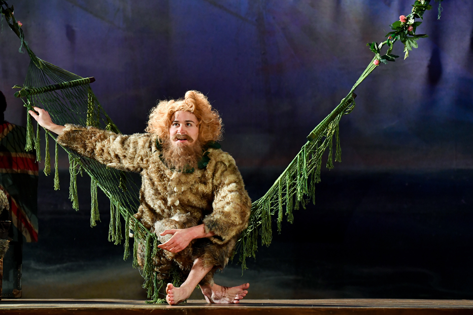 A male student in costume, sitting on a green net hammock.